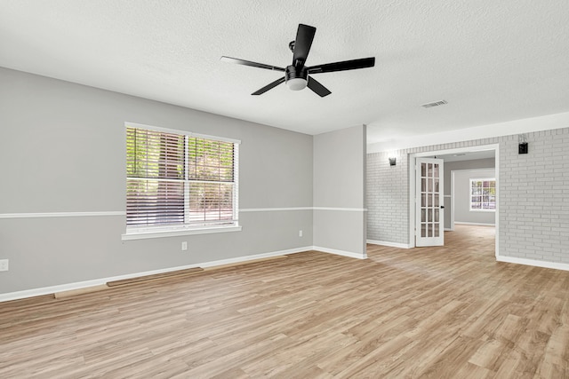 5700 Country Squire Dr, Milton, FL 32570 - empty room featuring a textured ceiling, brick wall, and light wood finished floors