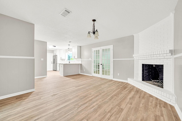 5700 Country Squire Dr, Milton, FL 32570 - unfurnished living room featuring light wood-style floors, an inviting chandelier, a textured ceiling, visible vents, and a sink