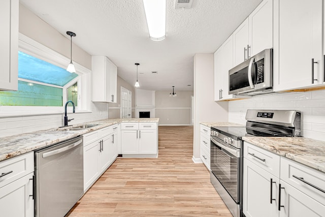 5700 Country Squire Dr, Milton, FL 32570 - kitchen with stainless steel appliances, white cabinets, light wood-type flooring, and a sink