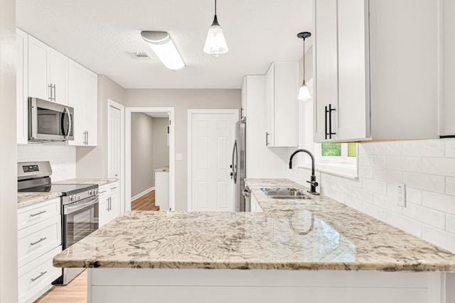 5700 Country Squire Dr, Milton, FL 32570 - kitchen featuring tasteful backsplash, light stone counters, a peninsula, appliances with stainless steel finishes, and a sink