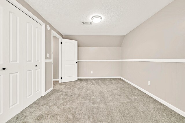 5700 Country Squire Dr, Milton, FL 32570 - unfurnished bedroom featuring a closet, baseboards, a textured ceiling, vaulted ceiling, and carpet flooring