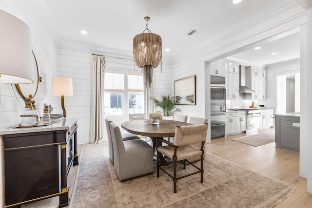 141 Sandchase Cir, Watersound, FL 32461 - dining room with ornamental molding, visible vents, light wood-style flooring, and wooden walls