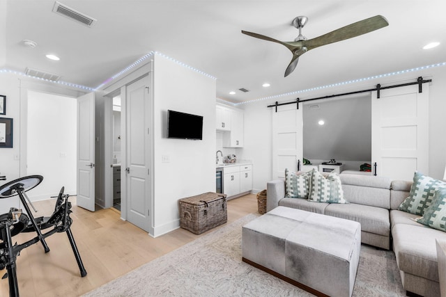 141 Sandchase Cir, Watersound, FL 32461 - living room with light wood-style flooring, a ceiling fan, visible vents, and a barn door