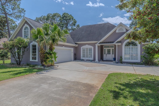 4030 Indian Trl, Destin, FL 32541 - view of front of home featuring stucco siding, driveway, an attached garage, a front lawn, and a shingled roof
