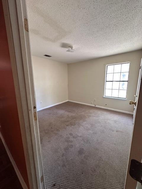 592 E Robinson Ave, Crestview, FL 32539 - unfurnished room with visible vents, baseboards, dark colored carpet, and a textured ceiling