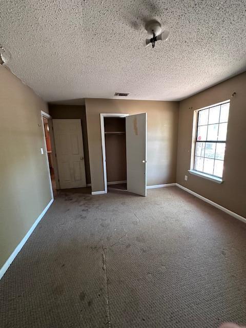 592 E Robinson Ave, Crestview, FL 32539 - unfurnished bedroom featuring baseboards, carpet, and a textured ceiling