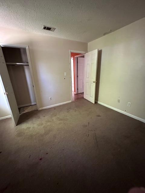 592 E Robinson Ave, Crestview, FL 32539 - unfurnished bedroom with carpet flooring, visible vents, baseboards, and a textured ceiling