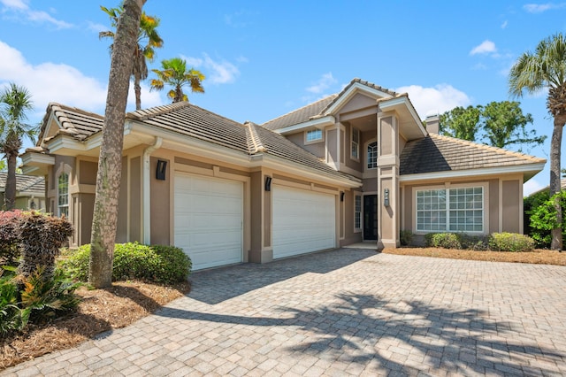 view of front of house with a tiled roof, a garage, and stucco siding