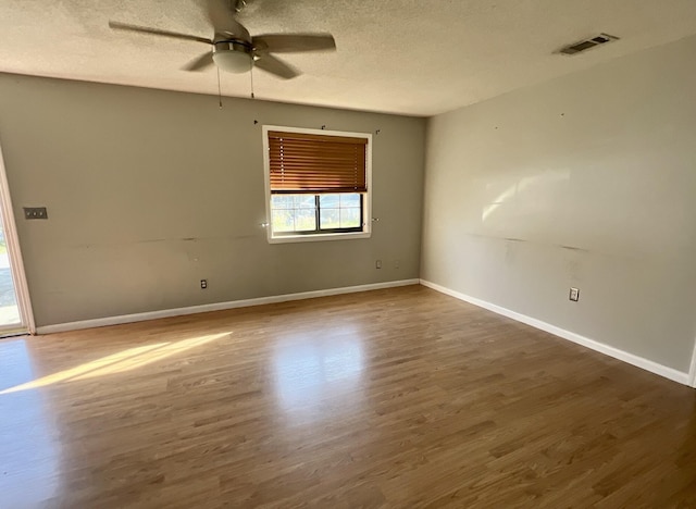 unfurnished room with baseboards, a textured ceiling, a ceiling fan, visible vents, and wood finished floors