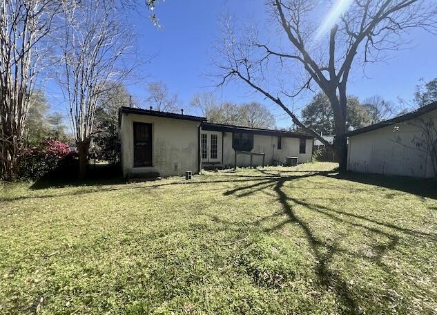 rear view of property featuring french doors, a lawn, and stucco siding