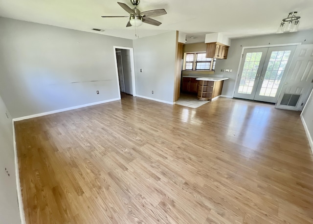 unfurnished living room featuring french doors, ceiling fan, light wood finished floors, and baseboards