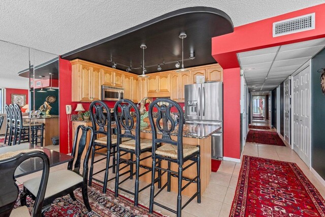 11619 Front Beach Rd Unit 201, Panama City Beach, FL 32407 - kitchen with visible vents, light brown cabinets, a breakfast bar, stainless steel appliances, and light tile patterned flooring