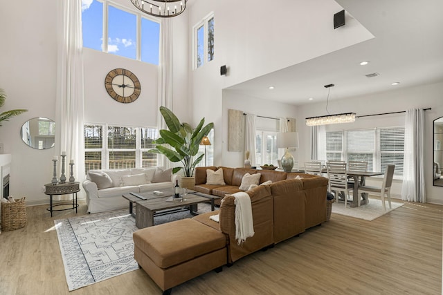 332 Somerset Bridge Rd, Santa Rosa Beach, FL 32459 - living room featuring a towering ceiling, an inviting chandelier, wood finished floors, and a healthy amount of sunlight
