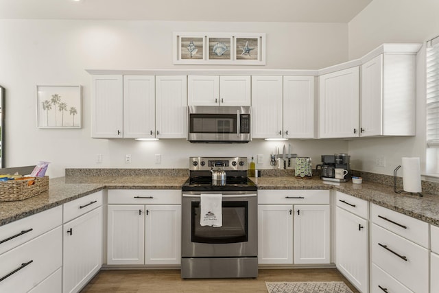 332 Somerset Bridge Rd, Santa Rosa Beach, FL 32459 - kitchen featuring a peninsula, light wood finished floors, white cabinetry, stainless steel appliances, and light stone counters