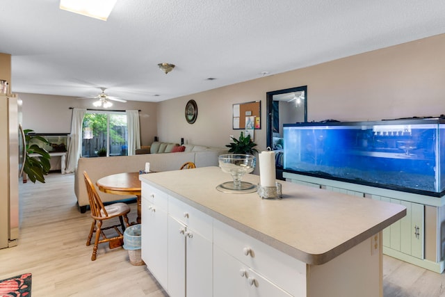 322 Apple Dr, Crestview, FL 32536 - kitchen with light wood-type flooring, open floor plan, a center island, a ceiling fan, and freestanding refrigerator