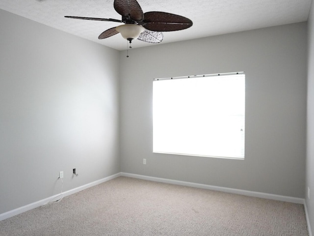 carpeted spare room featuring ceiling fan and baseboards