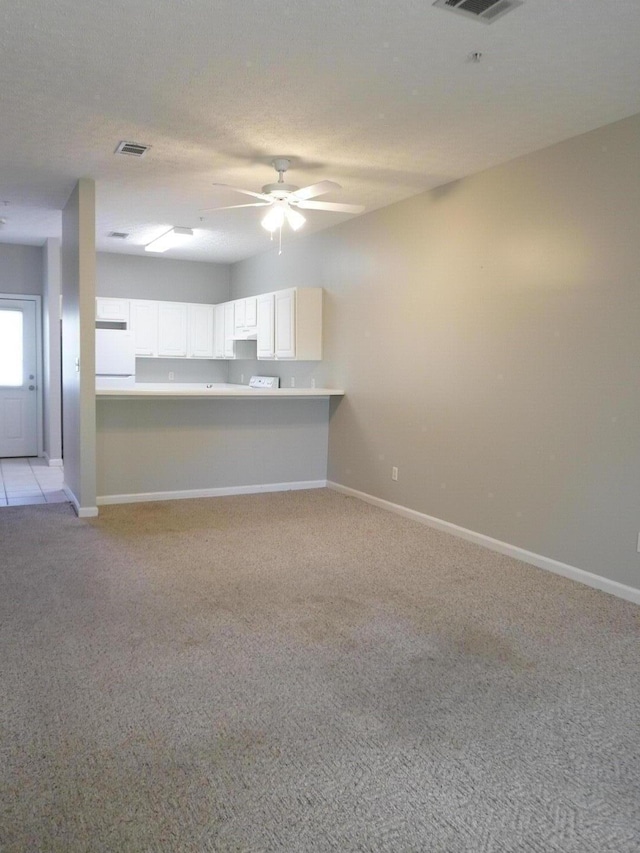 unfurnished living room featuring light colored carpet, visible vents, baseboards, and a ceiling fan