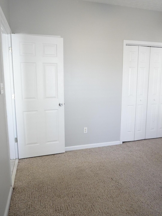 unfurnished bedroom with baseboards, carpet flooring, and a closet