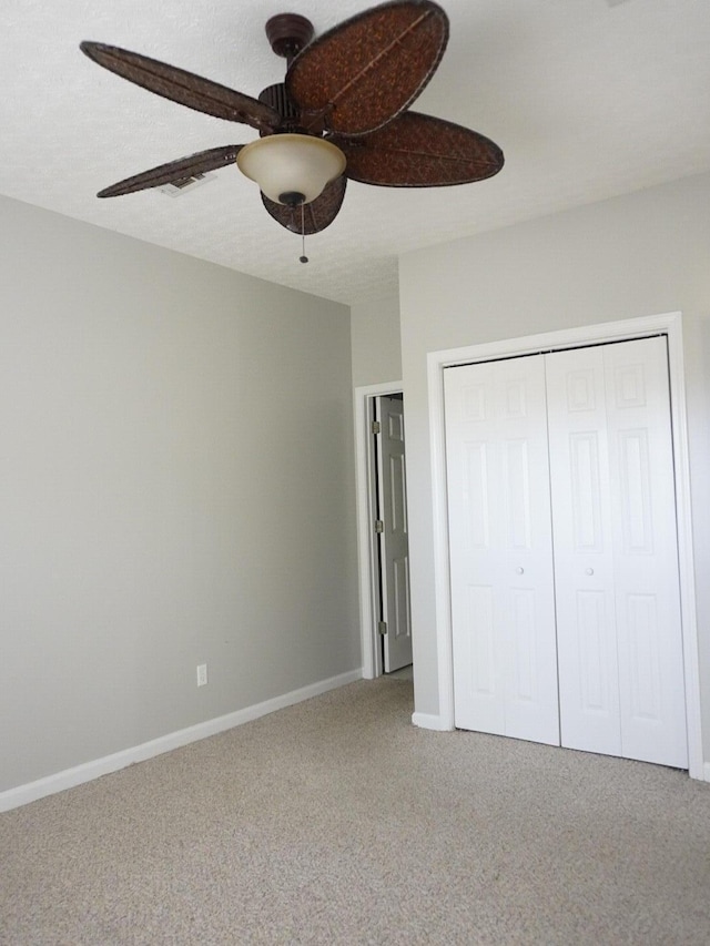 unfurnished bedroom featuring baseboards, carpet floors, a closet, and a ceiling fan