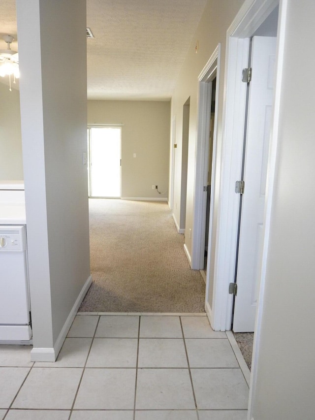 corridor featuring light tile patterned floors, light carpet, and baseboards