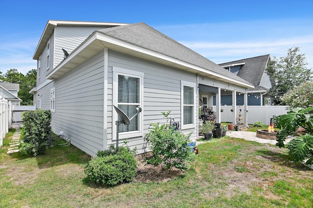 back of property featuring an outdoor fire pit and a shingled roof