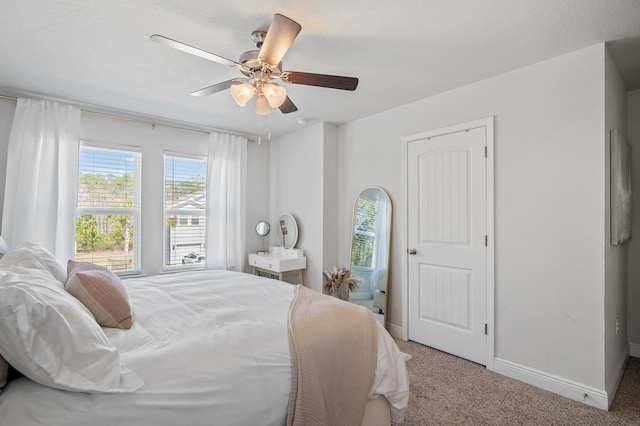 bedroom featuring ceiling fan, carpet flooring, baseboards, and multiple windows