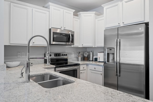 kitchen with white cabinetry, light stone counters, and appliances with stainless steel finishes