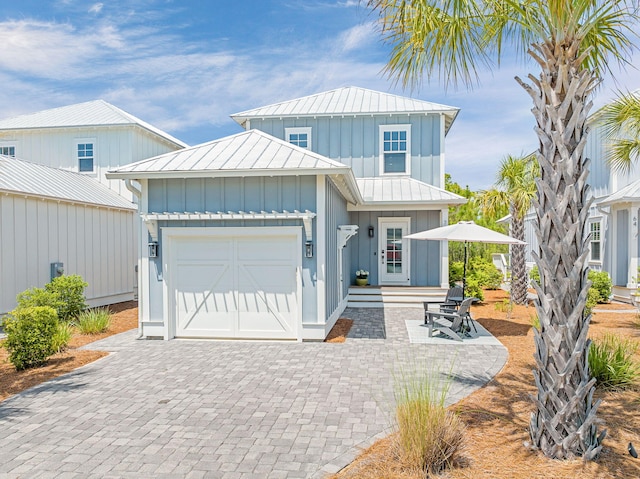 view of front of home with board and batten siding, a standing seam roof, metal roof, a garage, and driveway