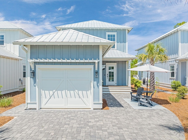 view of front of home with a standing seam roof, a garage, metal roof, driveway, and board and batten siding