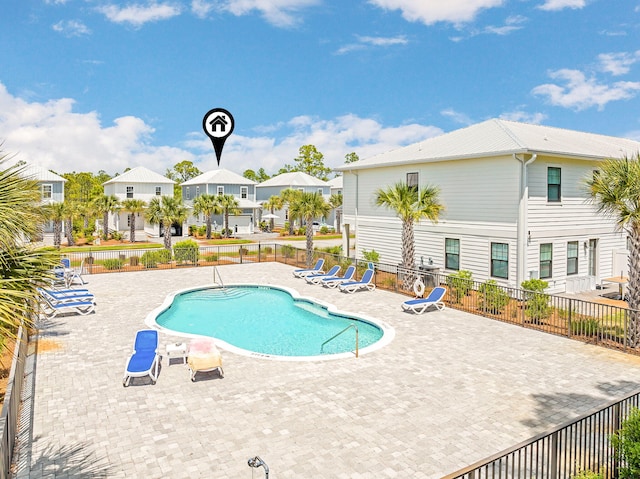 pool with a patio, fence, and a residential view