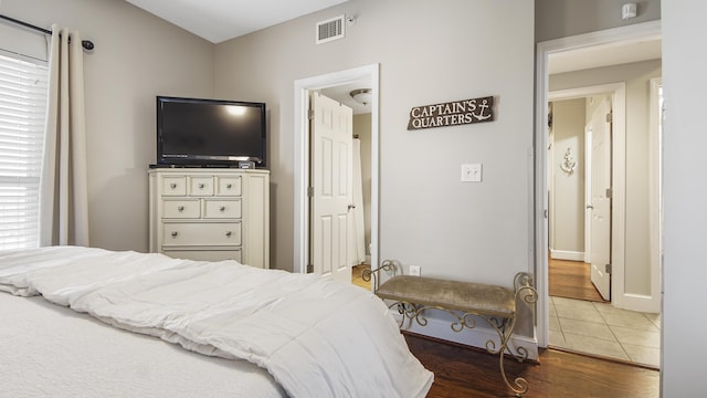 bedroom with visible vents, wood finished floors, and baseboards