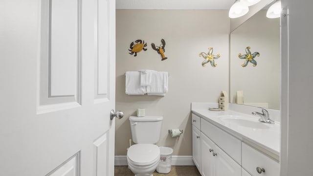 half bath featuring baseboards, toilet, tile patterned flooring, and vanity