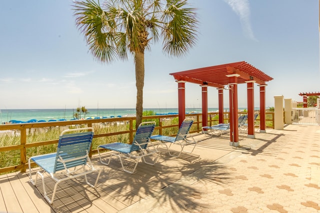 deck featuring a beach view, a pergola, and a water view