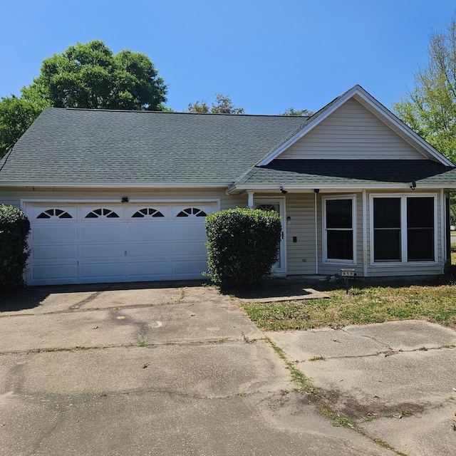 view of front of home featuring driveway, roof with shingles, and an attached garage