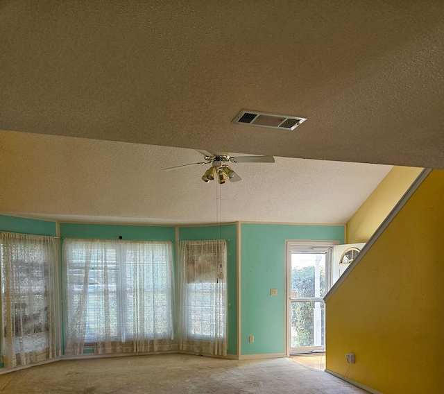 unfurnished room with carpet floors, a textured ceiling, ceiling fan, baseboards, and lofted ceiling
