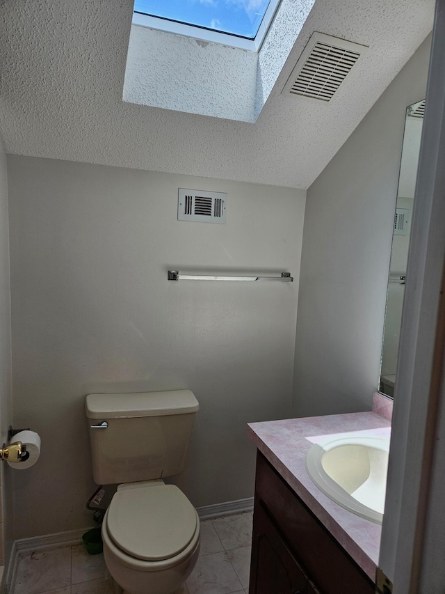 half bath with a skylight, a textured ceiling, toilet, vanity, and baseboards