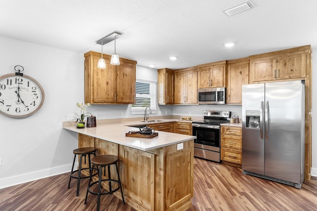 kitchen featuring a peninsula, visible vents, wood finished floors, and appliances with stainless steel finishes
