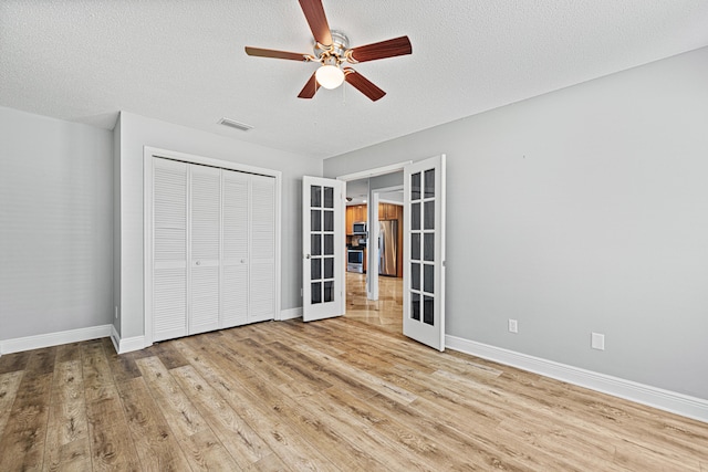 119 Long Pointe Dr, Mary Esther, FL 32569 - unfurnished bedroom featuring french doors, wood finished floors, a closet, stainless steel refrigerator with ice dispenser, and a textured ceiling