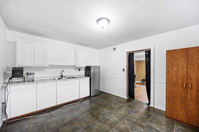706 Mary Ave, Fort Walton Beach, FL 32547 - kitchen with light stone countertops, a sink, visible vents, white cabinetry, and freestanding refrigerator