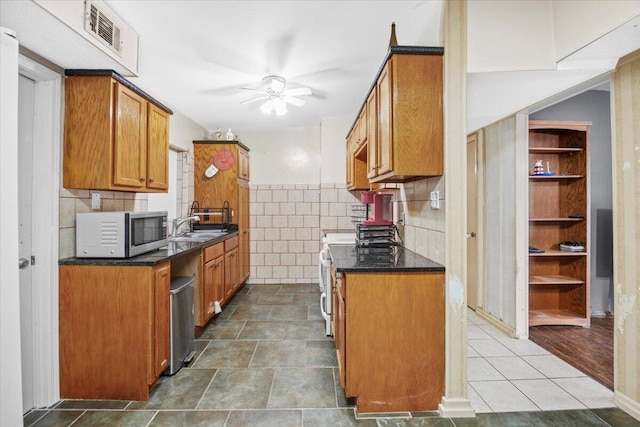 706 Mary Ave, Fort Walton Beach, FL 32547 - kitchen featuring stainless steel microwave, dark countertops, visible vents, a ceiling fan, and brown cabinetry