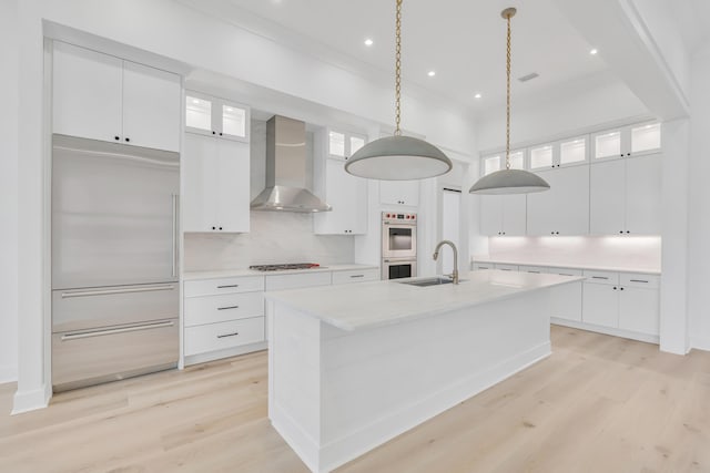 63 W Firethorn Cir Lot 65, Watersound, FL 32461 - kitchen with wall chimney exhaust hood, double oven, light wood-type flooring, gas cooktop, and an island with sink