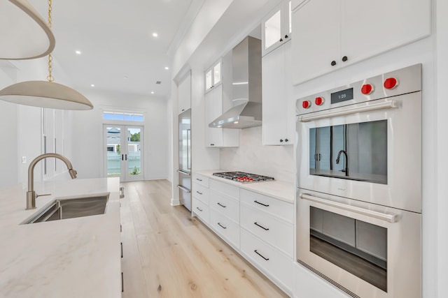 63 W Firethorn Cir Lot 65, Watersound, FL 32461 - kitchen featuring appliances with stainless steel finishes, wall chimney exhaust hood, light wood finished floors, white cabinetry, and recessed lighting