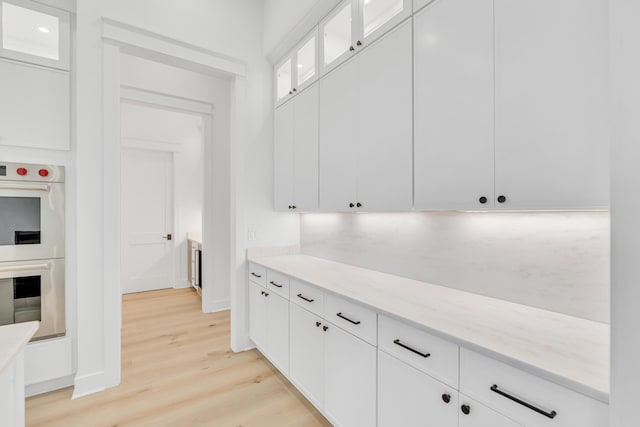 63 W Firethorn Cir Lot 65, Watersound, FL 32461 - kitchen featuring double oven, light wood-type flooring, white cabinetry, and glass insert cabinets