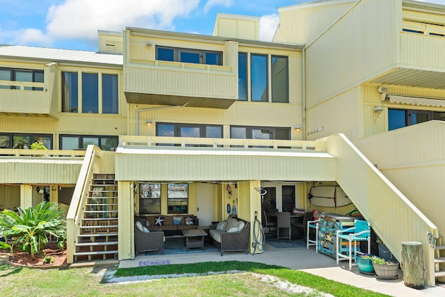 back of property with a patio, an outdoor living space, and stairway