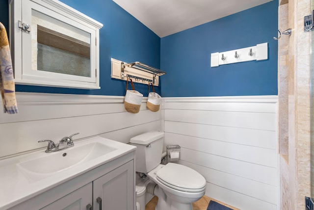 bathroom featuring toilet, wainscoting, and vanity
