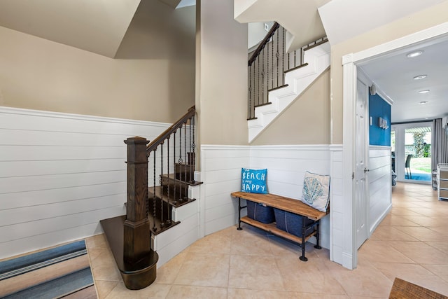 stairway featuring recessed lighting, tile patterned floors, and a wainscoted wall
