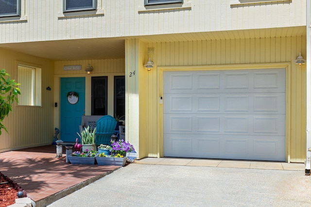 view of exterior entry featuring concrete driveway, covered porch, and a garage