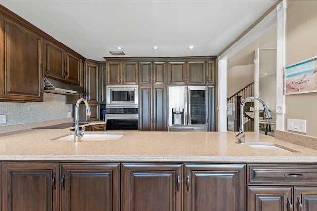 kitchen with a sink, dark brown cabinetry, stainless steel appliances, and under cabinet range hood