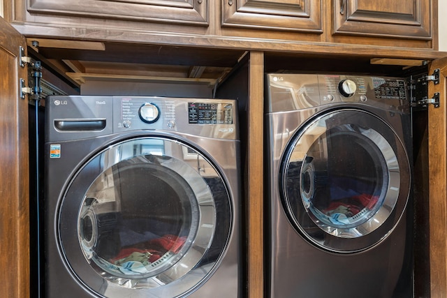 clothes washing area featuring cabinet space and washing machine and clothes dryer