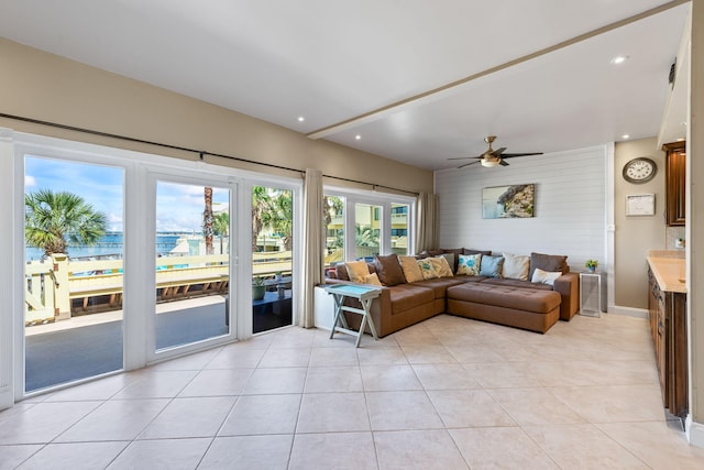 living area featuring a ceiling fan, baseboards, a water view, recessed lighting, and light tile patterned flooring